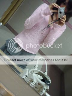 A pink sweater and grey skirt.